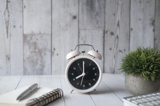 alarm clock ,notepad and pen on table .