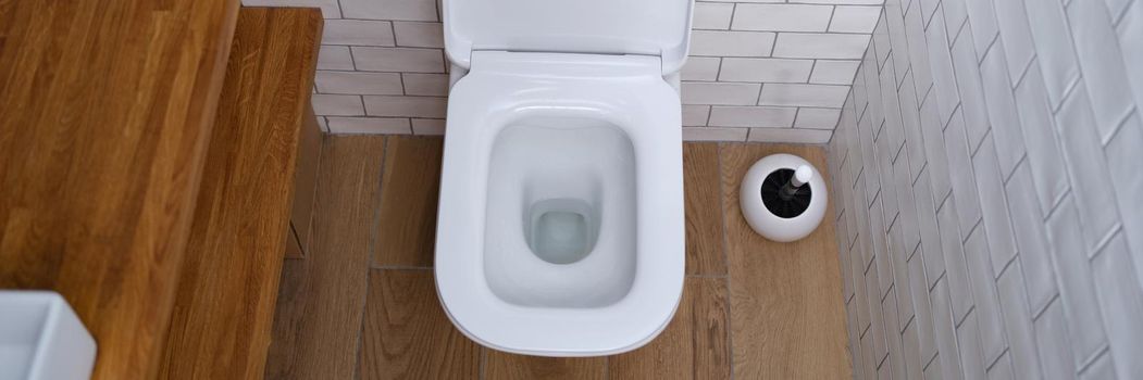 White clean ceramic toilet with silver wall button. Cleanliness and hygiene in the toilet concept