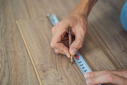 Man installing new wooden laminate flooring on a warm film floor. Infrared floor heating system under laminate floor.