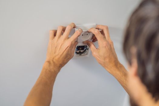 Master electrician installs a socket in the house.