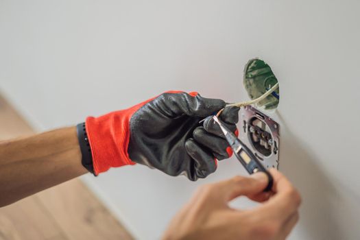 Master electrician installs a socket in the house.