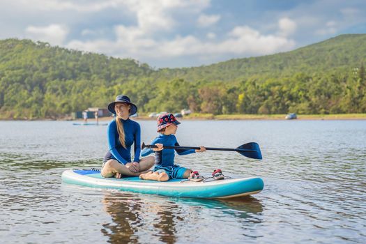 happy family of two, mother and son, enjoying stand up paddling during summer vacation.