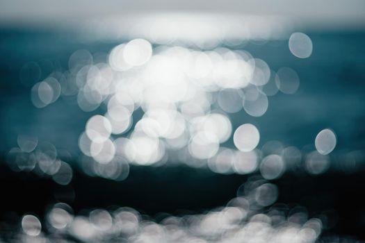 Abstract nature summer or spring ocean sea background. Small waves on water surface in motion blur with bokeh lights from sunrise.