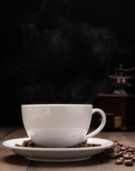 White coffee cup,roasted coffee beans,grinder on wooden table background