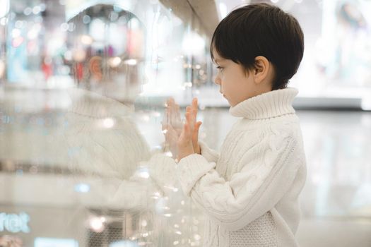 The boy in the winter shopping center does not look at the camera . Holiday shopping. Shopping trip