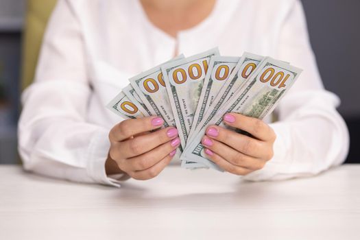 Stressed young woman calculating monthly home expenses. Hands counting US Dollar bills or paying in cash on money background. Concept of investment, success, financial prospects or career advancement