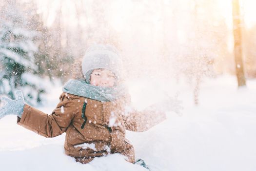 The boy throws snow in winter lifestyle . Winter walks. An article about children's winter leisure. Entertainments