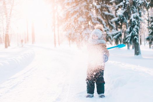 The boy throws snow with a shovel lifestyle . Winter walks. An article about children's winter leisure. Entertainments
