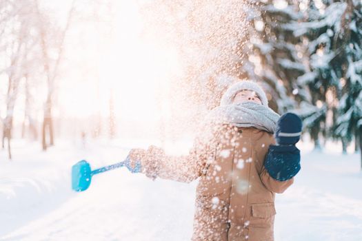 The boy throws snow with a shovel lifestyle . Winter walks. An article about children's winter leisure. Entertainments