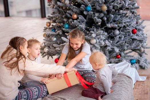 Happy kids having fun and opening presents near christmas tree.