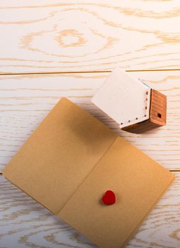 Little model house  and a notebook on a parquet background