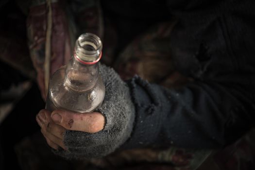 Caucasian Homeless Men Wearing Fingerless Gloves with a Bottle of Vodka Close Up.