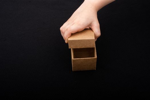 Hand opening a brown cardboard box on black backgrounds