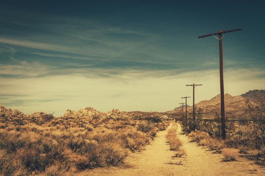 Mojave Desert Rural Sandy Road. Southern California Countryside Theme with Wooden Electric Poles.