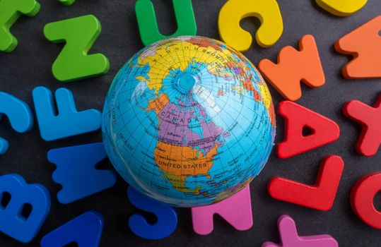 Earth globe model on colorful letters on a black background