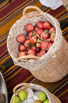 Red and green apples in straw baskets in display