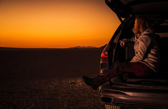 Caucasian Woman in Her 40s Enjoying Scenic California Mojave Desert Sunset From Her Sport Utility Car Cargo Section. Travel and Recreation Theme.