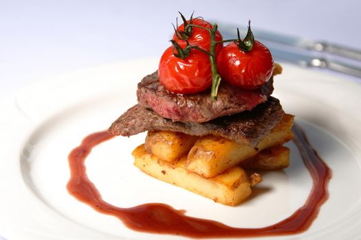 A beef steak with tomatoes and french fries