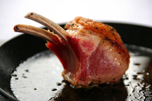 A rack of lamb searing in a black pan