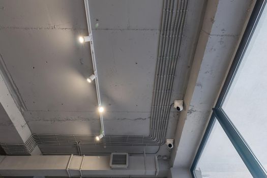 Interior architecture and ceiling design of industrial loft building decorated with modern lamps, glass windows and wall speakers