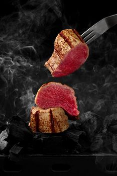 Pieces of juicy beef tenderloin cooking on grill over smoking embers. Freeze barbecue motion concept