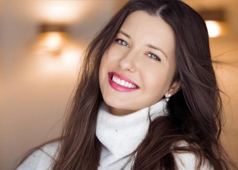 Winter portrait and Christmas holiday look. Beautiful woman in white sweater with long brown hair and glamour makeup, hairstyle model and xmas fashion.