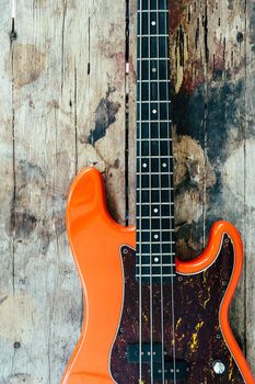 orange electric bass guitar on wood background with copy space