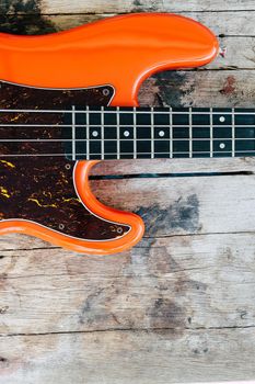 orange electric bass guitar on wood background with copy space