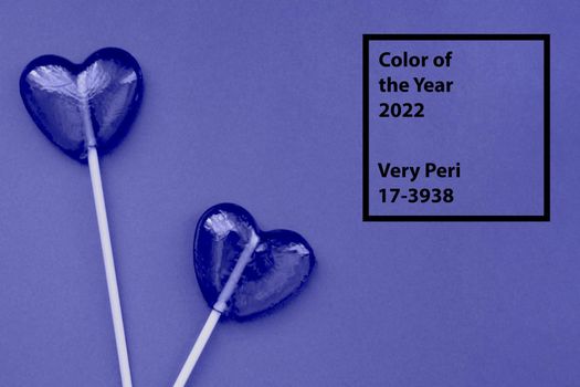 Purple lollipops in the form of hearts on a purple background. The concept of Valentine's Day. Demonstrating the colors of 2022 - Very Peri.
