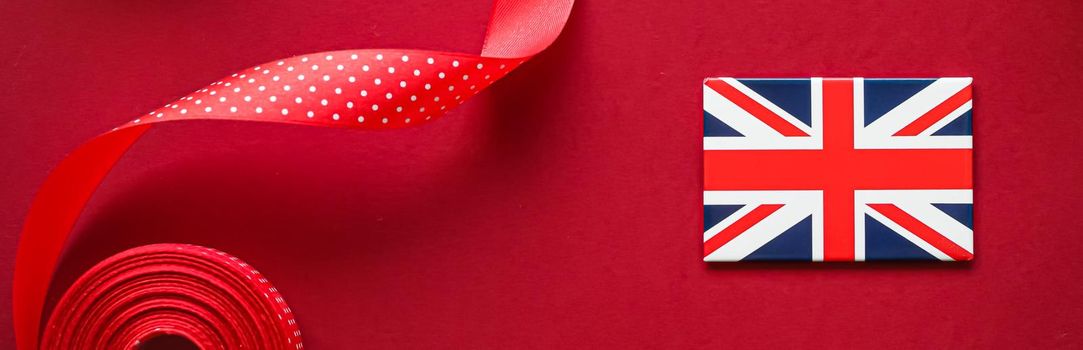 British Christmas tradition and holiday design concept. Union Jack flag of Great Britain and xmas ornaments and decoration on red background as flatlay top view.