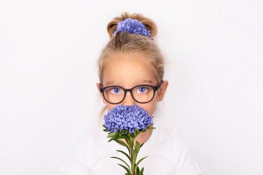 Child girl holding one purple aster flower isolated on white background. International mothers day concept. Trendy banner with 2022 color of the year very peri.