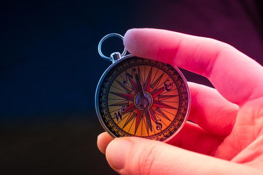 Hand is holding a magnetic compass on black background