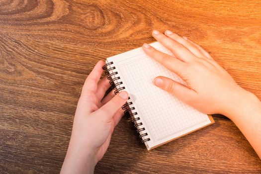White notebook in hand on  a brown color background