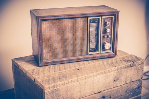 Aged Radio on Wooden Crate. Vintage Color Grading.
