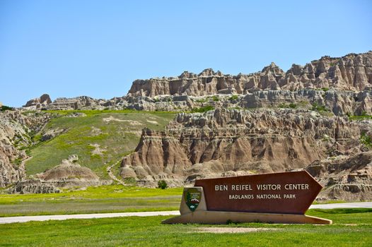 Ben Reifel Visitor Center Sign in Badlands National Park. Badlands Landscape in the Background.