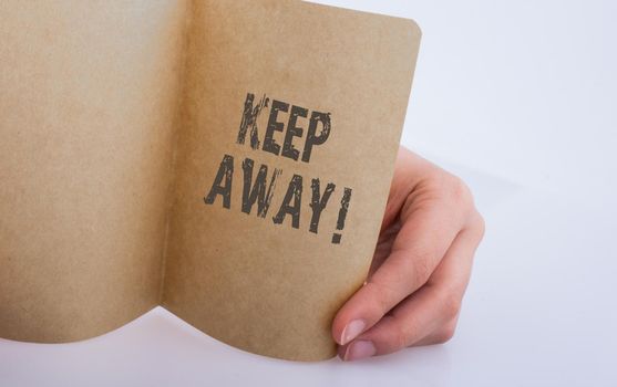 Hand holding a sheet of paper with keep away wording