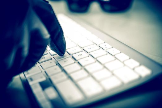 Hacker in Work. Hacker Hand in Black Glove Typing on the Keyboard. Closeup Photo Concept. 
