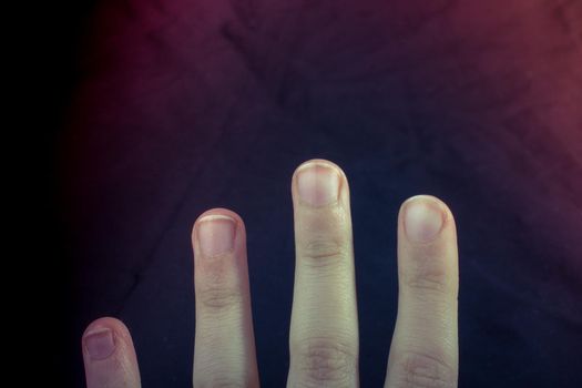 Four fingers of a child hand partly seen in black background