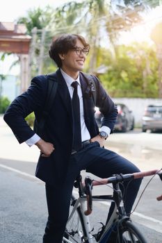 Handsome young asian businessman in suit have smiling with bicycle go to work at morning.