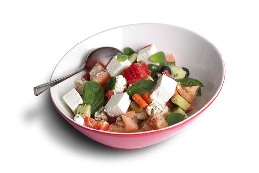 A owl of greek salad with spoon on white