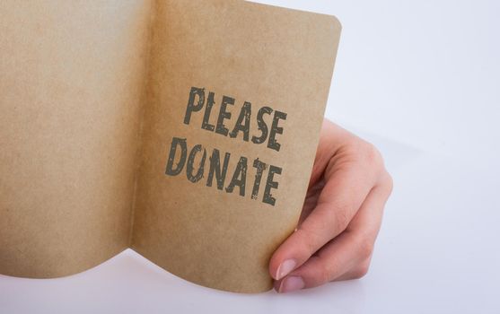 Hand holding a sheet of paper   with please donate wording