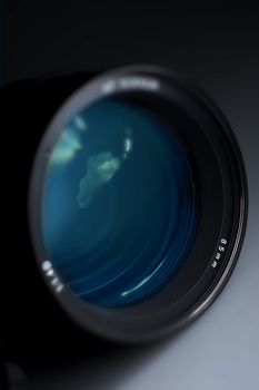 Professional Photography Prime Lens Glass - Blue Light Reflections. Dark Background Vertical Studio Photography. 