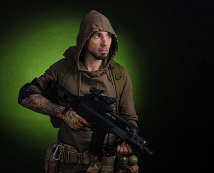 man Stalker with a gun with an optical sight and a backpack on a dark background with emotions looking, aiming, watching, sneaking