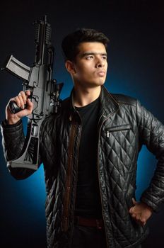 Asian guy in black jacket and automatic rifle