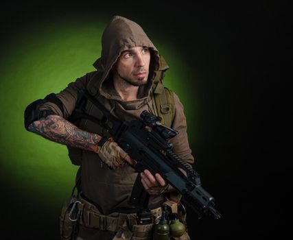 man Stalker with a gun with an optical sight and a backpack on a dark background with emotions looking, aiming, watching, sneaking