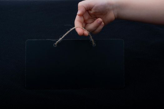 Rectangular shaped black notice board in hand on black background