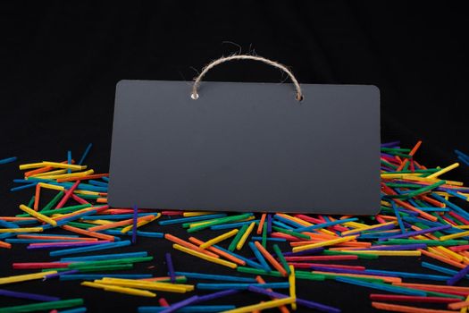 Rectangular shaped black notice board on colorful sticks on black