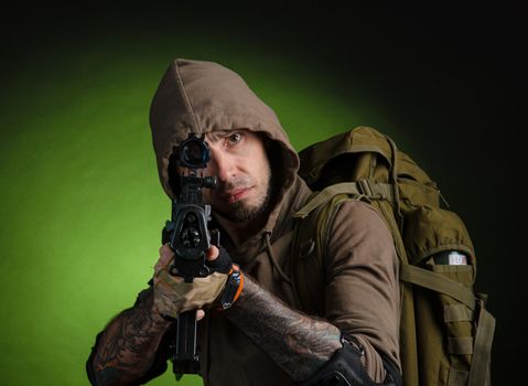 the man Stalker with a gun with an optical sight and a backpack on a dark background with emotions looking, aiming, watching, sneaking