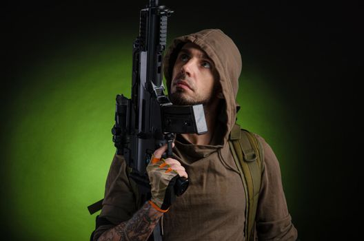 the man Stalker with a gun with an optical sight and a backpack on a dark background with emotions looking, aiming, watching, sneaking