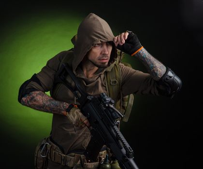 the man Stalker with a gun with an optical sight and a backpack on a dark background with emotions looking, aiming, watching, sneaking